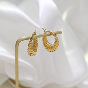 Detailed macro view of gold-plated croissant hoop earrings with unique spiral texture