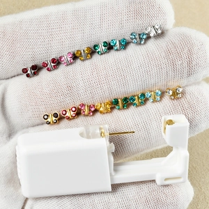 Macro shot of disposable ear piercing gun set with 12 pairs of colorful butterfly studs