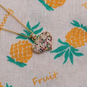 Minimalist gold heart pendant necklace with colorful zircon stones on textured fabric