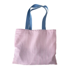 Pink striped canvas tote bag with blue handles shown on white background