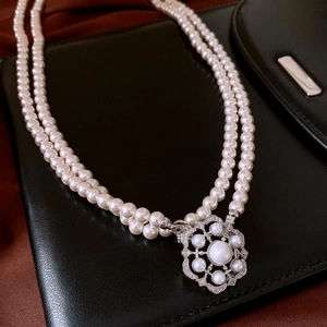 Close-up of double-layer white pearl necklace with a vintage hollow snowflake pendant
