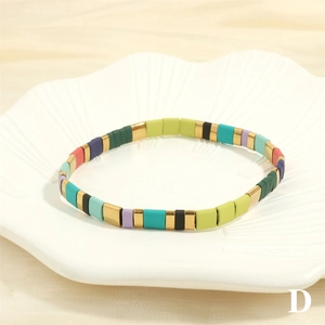 Detail view of colorful bohemian enamel tile bracelet with elastic cord on white tray