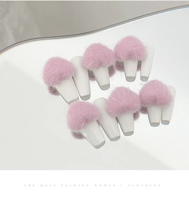 Detail of pink fluffy heart pom-pom nail charms with magnetic base on mirrored surface