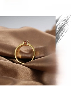 Macro detail of gold plated ring featuring red zircon stone and intricate hollow metalwork