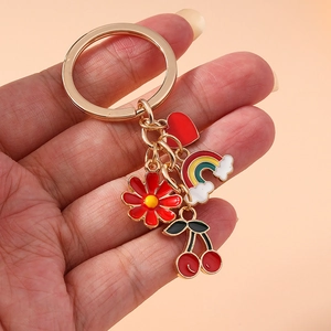 Golden keychain featuring colorful enamel flower, rainbow, heart, and cherry charms