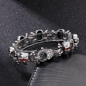 Detailed view of silver skull bracelet with red rhinestone eyes and lobster clasp