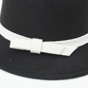 Detail of a black felt hat featuring a contrast white bow and precision stitching
