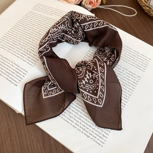 Detailed texture of dark brown paisley silk scarf tied on a vintage English art book