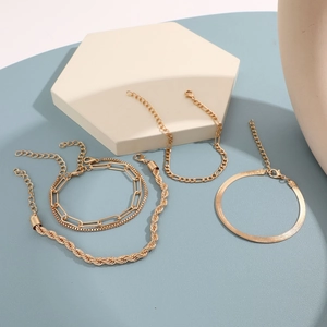 Detailed close-up of four-piece gold chain bracelet set on geometric props