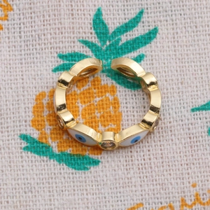 Detail of adjustable gold ring with wave texture and blue evil eye enamel charms