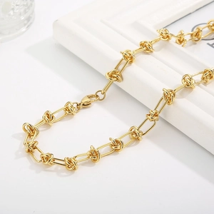 Close-up of polished gold-tone knot-link chain necklace with high-gloss finish