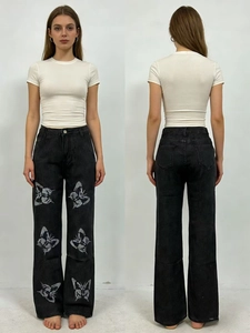 Détail d'un jean noir taille haute avec imprimés papillon argentés et poches à l'arrière