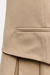 Dettaglio ravvicinato del tessuto plissettato kaki e cuciture della tasca del vestito
