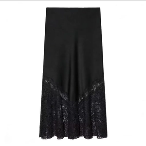 Détail de la jupe mi-longue en satin noir avec de larges finitions en dentelle délicate