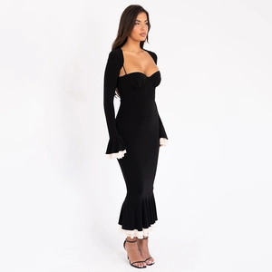 Detail of black mermaid dress featuring white ruffled hemline and flared long sleeves