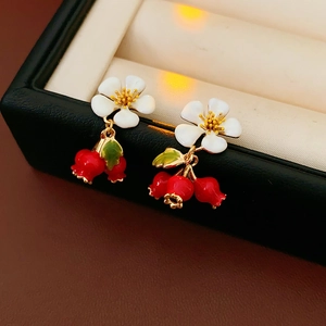 Macro shot of vintage floral earrings with red berry pendants in a black jewelry box