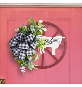 Detail of farmhouse cow wheel wreath with buffalo plaid bow and Welcome sign on a pink door