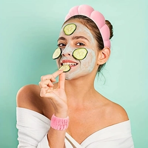 Pink plush headband and wristbands worn by a model in a relaxing home skincare setting