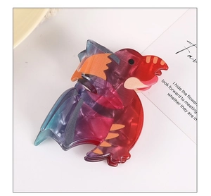 Detail of cute dinosaur hair claw clip with colorful gradient acetate finish on white surface