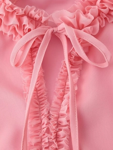 Detail of pink chiffon blouse featuring ruffled neckline and delicate tie bow detail