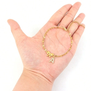 Macro view of golden bow bracelet with sparkling letter A pendant on hand