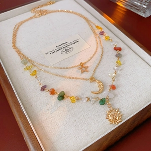 Close-up of triple-layered gold necklaces with sun moon stars and multicolor stone beads