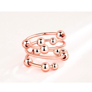 Close-up of rose gold layered anxiety ring with rotatable beads on a white surface