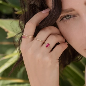 Detail of twisted gold ring with a rectangular pink gemstone and micro-pave accents
