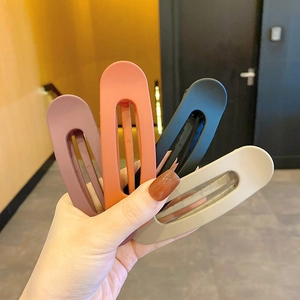 Morandi matte large hair clips in pink, coral, black and beige colors held by hand
