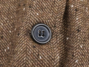 Vue macro d'un bouton gris foncé sur le tissu en tweed à chevrons marron