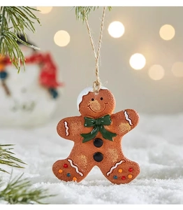 Detail of resin gingerbread man ornament with white icing and green bow on snow