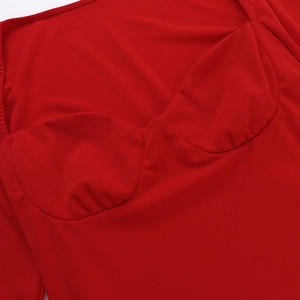 Détail de la robe rouge montrant le plissage au buste et la texture du tissu en maille
