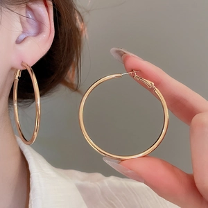 Detailed close-up of large polished gold hoop earrings with a sleek metallic mirror finish