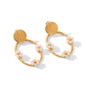 Détail de boucles d'oreilles créoles en acier 18K avec texture martelée et fleur en perle