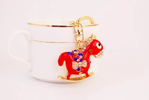 Close-up of red rocking horse keychain with multicolor rhinestones on ceramic cup