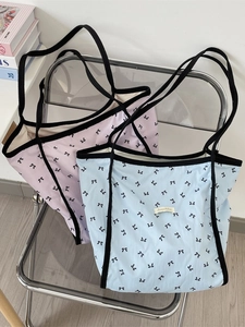 Borse tote rosa e blu con stampe di fiocchi esposte su una sedia moderna minimalista
