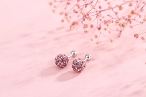 Detail of pink crystal pave ball stud earrings with silver screw back on a floral background