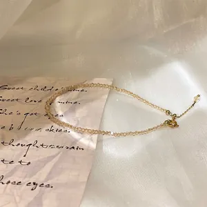 Close-up of champagne crystal beaded anklet with adjustable gold lobster clasp on white fabric