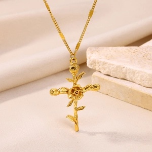 Detailed view of a gold-plated rose cross necklace on a textured white fabric background