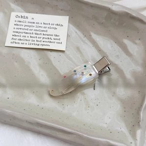 Elegant water drop hair clip with colorful rhinestones on a ceramic tray display