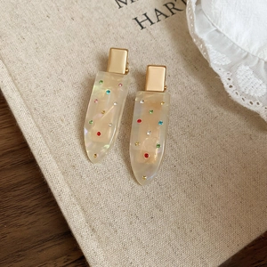 Detailed macro view of two cream hair clips with colorful rhinestones on rustic linen fabric