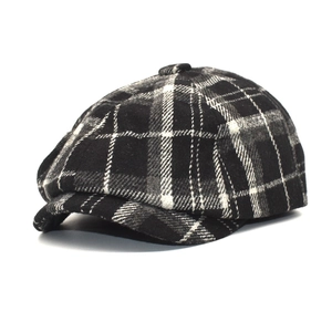 Detailed close-up of a black and white plaid wool newsboy cap showing texture and shape