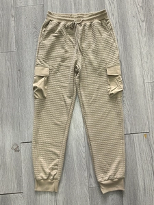 Detail of khaki cargo joggers showing waffle quilted texture and elastic drawstring waist