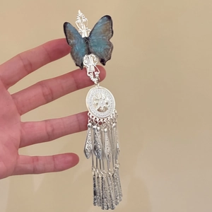 Detail view of a blue resin butterfly hair clip with long silver tassels for Hanfu style