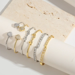 Modern gold and silver Love bangles with heart charms and pavé stones on display stand