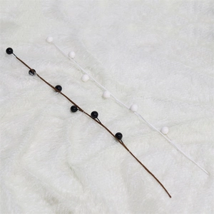 Detail of decorative white and black pearl branches on a soft white plush surface