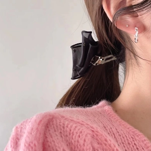 Close-up of a black satin bow hair clip styled on long dark hair with a silver clasp