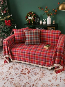 Detailed view of red plaid sofa cover and pillow with fringes in a Christmas setting