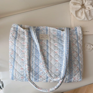 Detailed close-up of quilted floral tote bag with blue rabbit prints and ribbon patterns