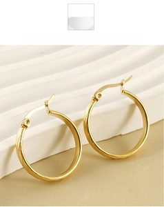 Macro detail of gold-plated hoop earrings with textured spiral patterns and secure clasp